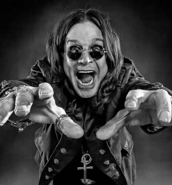 Um jovem Ozzy Osbourne, no final dos anos 60, em preto e branco, em uma encruzilhada de uma rua industrial de Birmingham. De um lado, uma fábrica sombria; do outro, um palco com uma luz brilhante. Ele está olhando para o palco com uma expressão de determinação. O estilo é de uma foto de filme granulado, dramático, alta resolução, proporção 16:9.